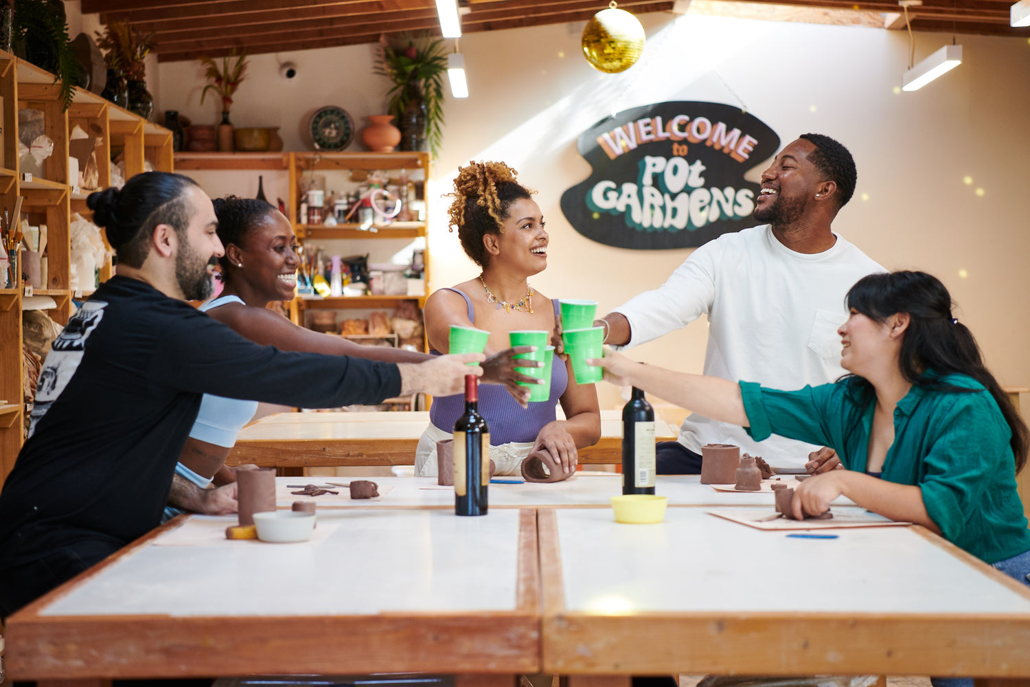 Group of people sitting at a table in a casual setting with a 'Welcome to POT Garden' sign in the background.